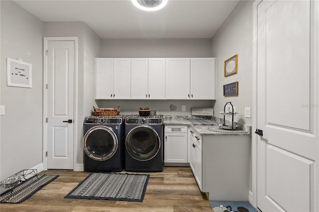 laundry area featuring separate washer and dryer, cabinets, and wood-type flooring