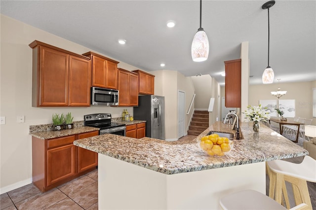 kitchen featuring sink, kitchen peninsula, decorative light fixtures, a kitchen bar, and appliances with stainless steel finishes