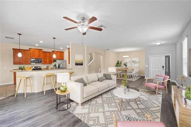 living room featuring ceiling fan with notable chandelier and light wood-type flooring