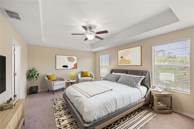 bedroom featuring a raised ceiling, ceiling fan, and carpet flooring