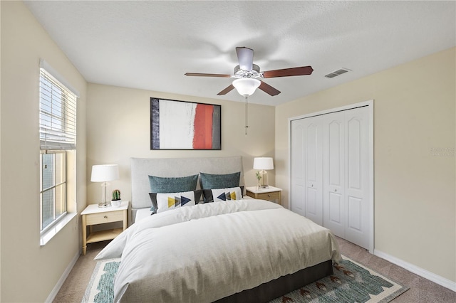 carpeted bedroom featuring a textured ceiling, a closet, and ceiling fan