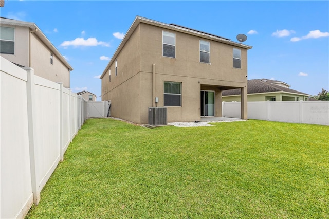 rear view of property with a yard, a patio, and central air condition unit