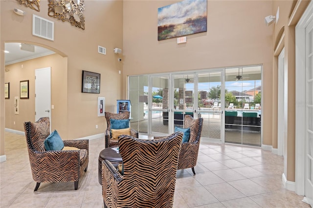 living room with crown molding, light tile patterned floors, and a high ceiling