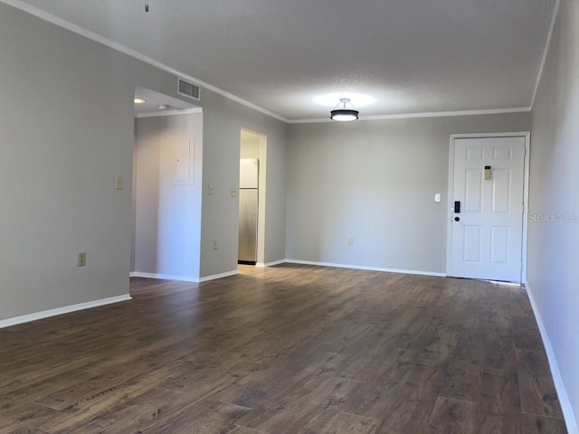 empty room with a textured ceiling, crown molding, and dark wood-type flooring