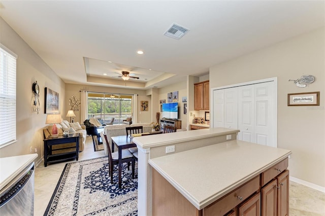 kitchen with stainless steel dishwasher, a raised ceiling, ceiling fan, light tile patterned floors, and a center island