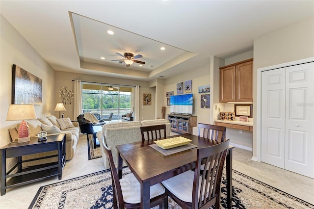 dining area with ceiling fan and a raised ceiling