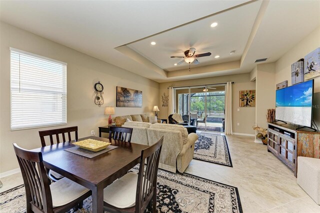 dining room with ceiling fan and a tray ceiling