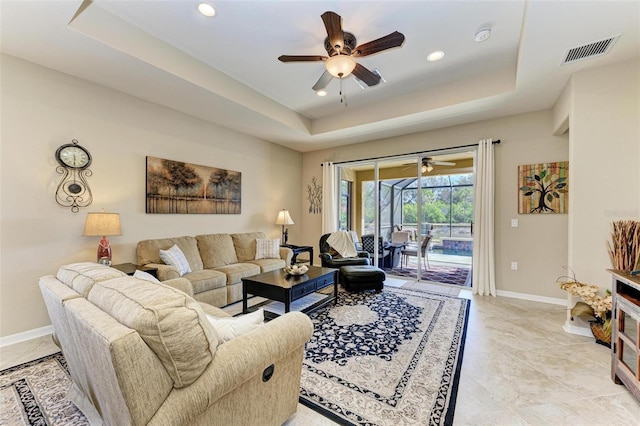 living room featuring ceiling fan and a tray ceiling