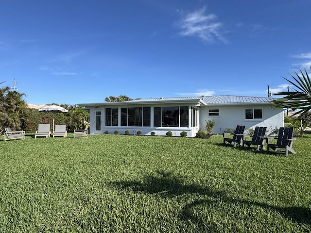 rear view of property with a lawn and a sunroom