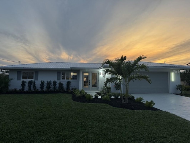 ranch-style home with a garage, a yard, and french doors