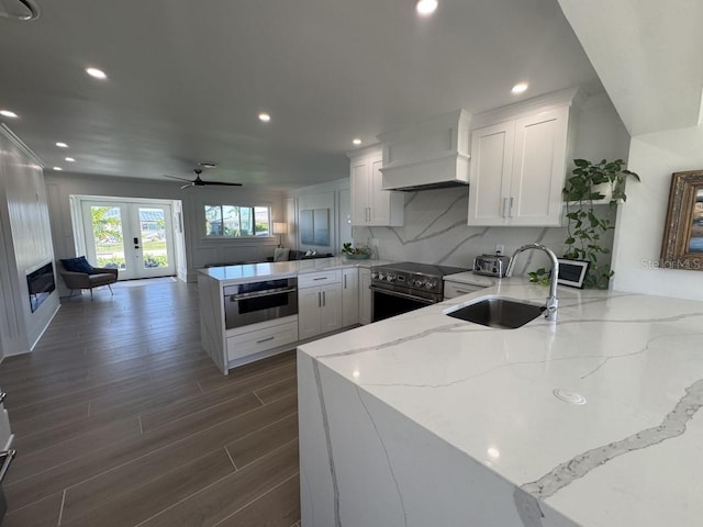 kitchen featuring kitchen peninsula, custom range hood, sink, oven, and black / electric stove