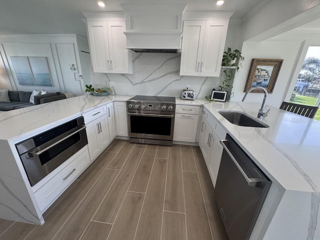 kitchen featuring kitchen peninsula, appliances with stainless steel finishes, white cabinets, and sink