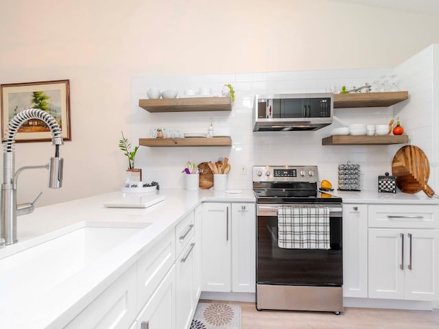 kitchen featuring decorative backsplash, appliances with stainless steel finishes, sink, white cabinets, and light hardwood / wood-style floors