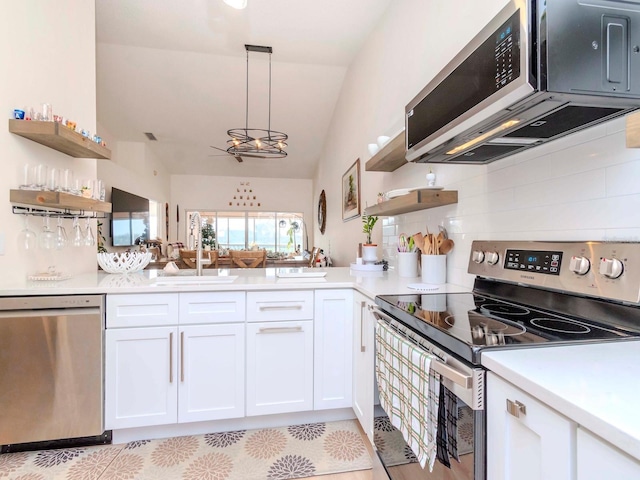 kitchen featuring decorative light fixtures, stainless steel appliances, vaulted ceiling, and white cabinetry