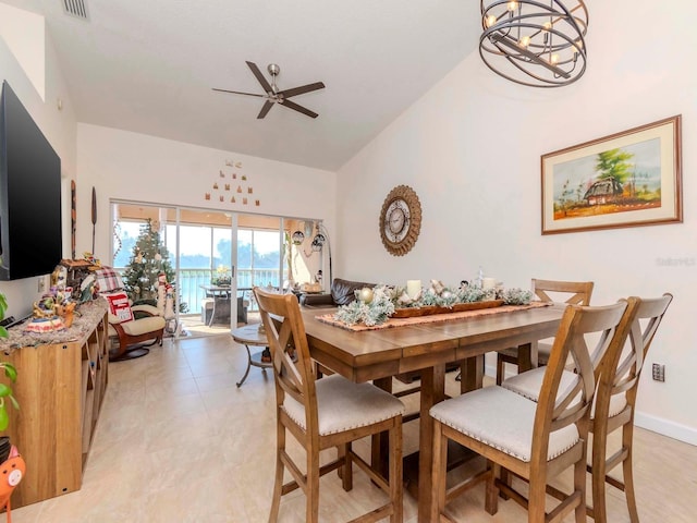 dining room featuring ceiling fan with notable chandelier and a water view