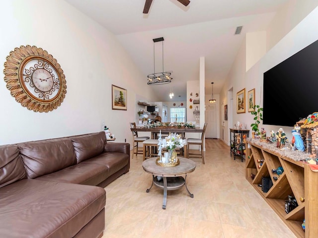 living room featuring light tile patterned floors, ceiling fan with notable chandelier, and high vaulted ceiling