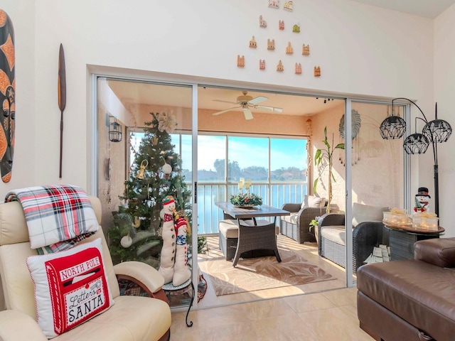 living room featuring ceiling fan, a water view, and light tile patterned floors