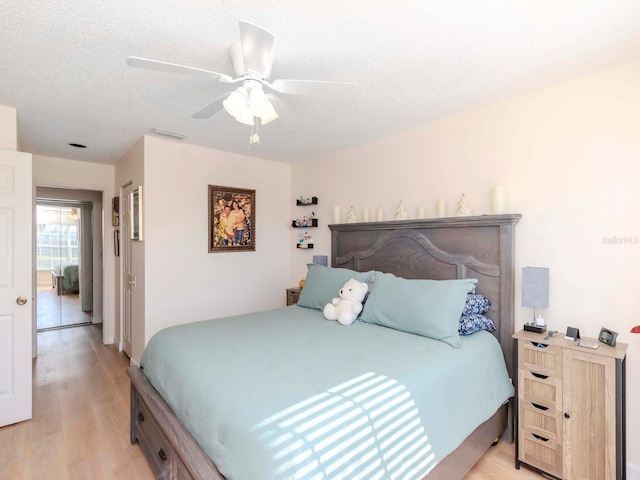 bedroom with a textured ceiling, light hardwood / wood-style floors, and ceiling fan