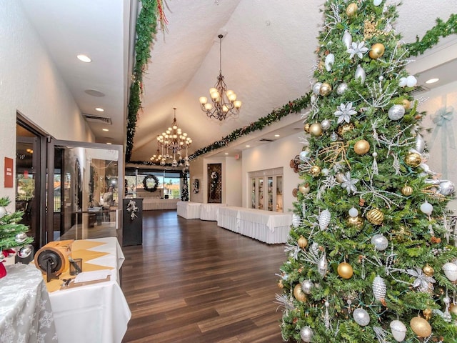 interior space with a textured ceiling, vaulted ceiling, dark wood-type flooring, and a chandelier