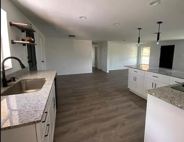 kitchen featuring white cabinets, light stone countertops, a kitchen island with sink, and sink