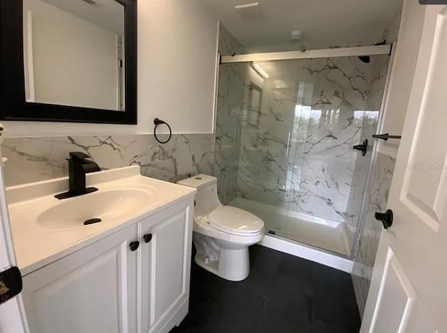 bathroom featuring vanity, toilet, an enclosed shower, and tile walls