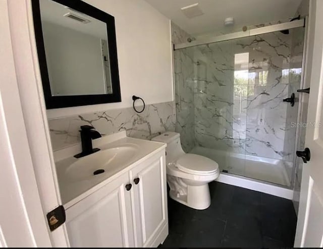 bathroom with vanity, tile patterned floors, toilet, walk in shower, and tile walls