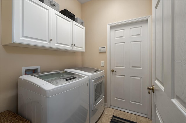 clothes washing area featuring cabinets, independent washer and dryer, and light tile patterned floors