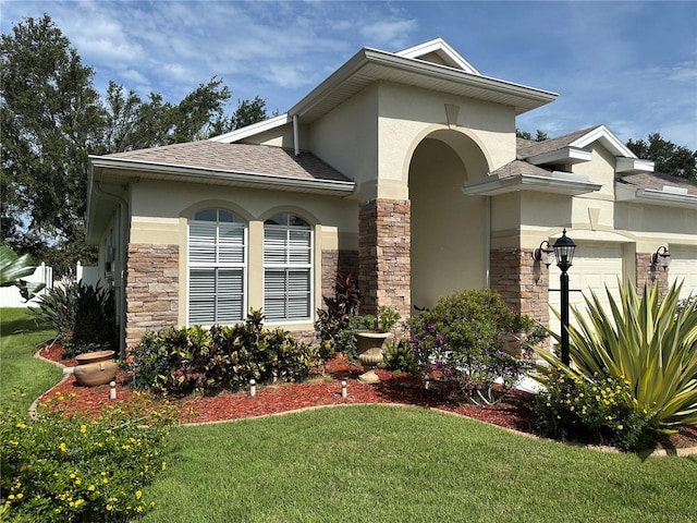 3439 101st Ave E, Parrish, FL 34219 - view of property exterior with stucco siding, stone siding, an attached garage, a lawn, and roof with shingles
