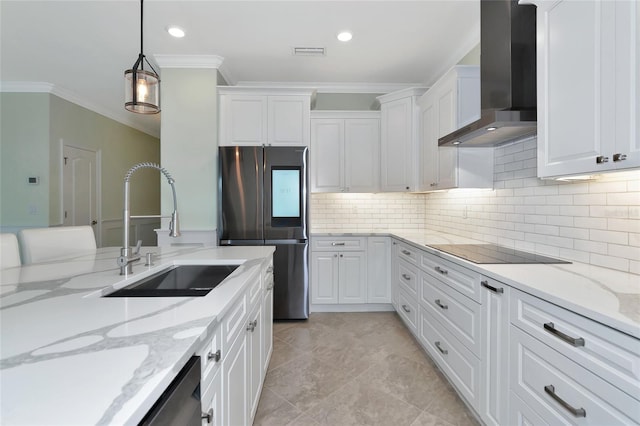 kitchen featuring appliances with stainless steel finishes, pendant lighting, sink, white cabinetry, and wall chimney range hood