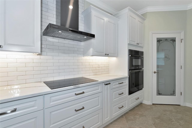 kitchen with black appliances, light stone counters, white cabinetry, wall chimney range hood, and tasteful backsplash