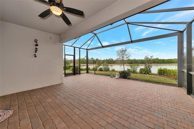 view of patio / terrace featuring ceiling fan, a water view, and glass enclosure