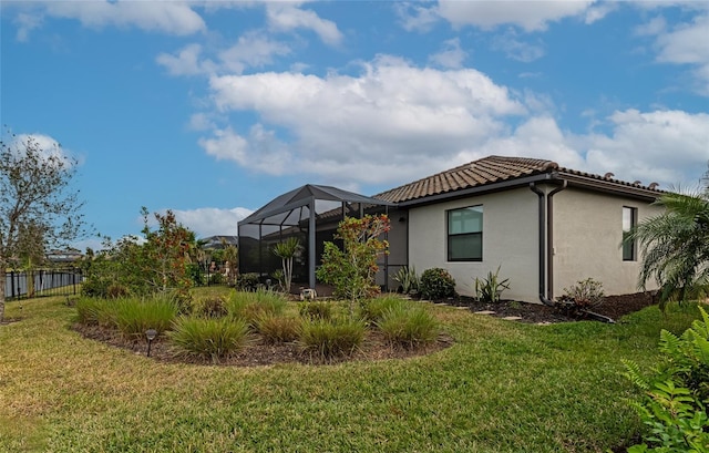 rear view of house featuring glass enclosure and a lawn