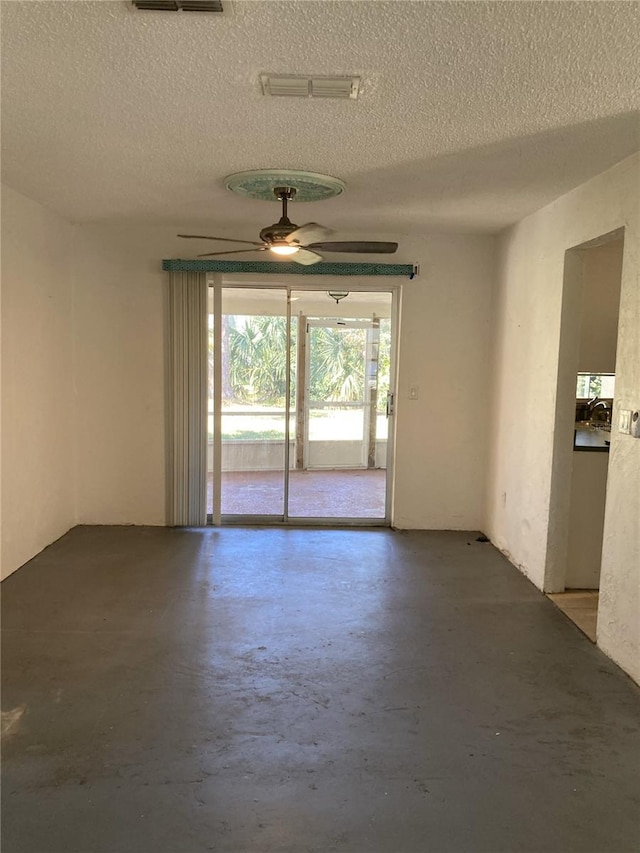 spare room featuring ceiling fan, a textured ceiling, and concrete floors