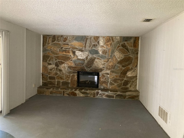 unfurnished living room with a textured ceiling, a fireplace, wooden walls, and concrete floors