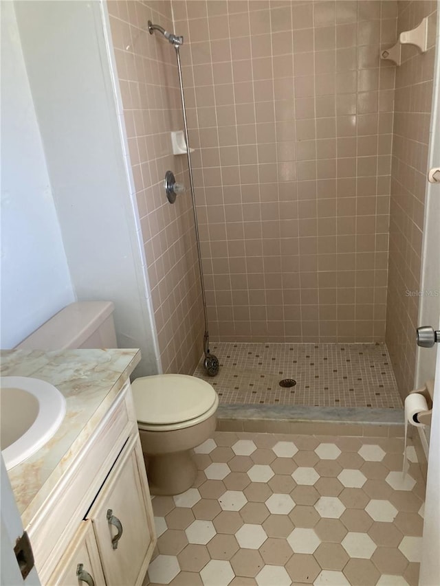 bathroom featuring a tile shower, vanity, and toilet