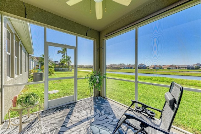 sunroom with a wealth of natural light, ceiling fan, and a water view