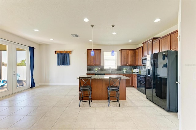 kitchen featuring french doors, stone countertops, a breakfast bar, a kitchen island, and black appliances