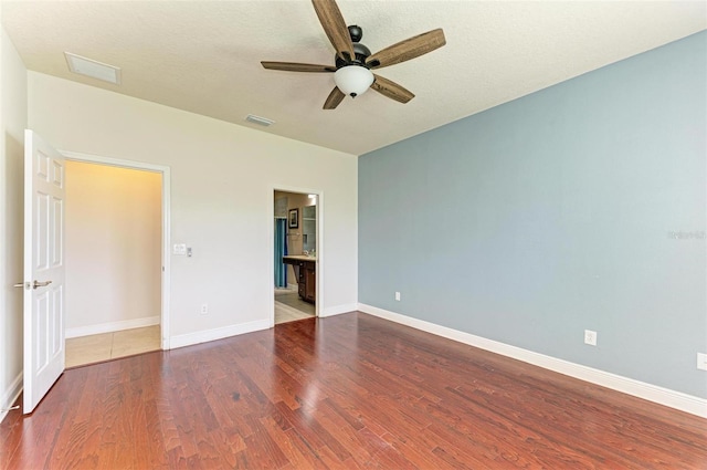 unfurnished bedroom featuring ensuite bathroom, ceiling fan, and dark wood-type flooring