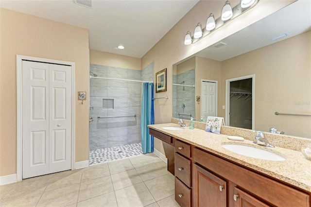 bathroom with tile patterned flooring, vanity, and tiled shower