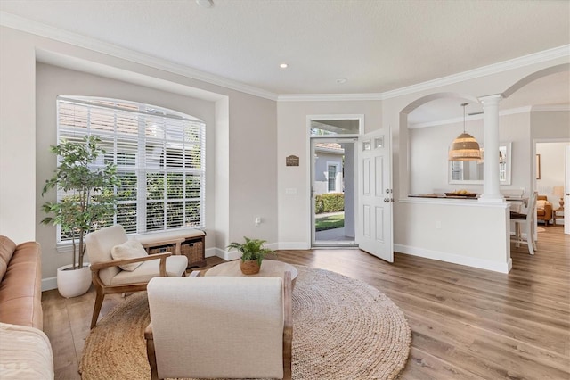 sitting room with hardwood / wood-style flooring, ornate columns, and crown molding