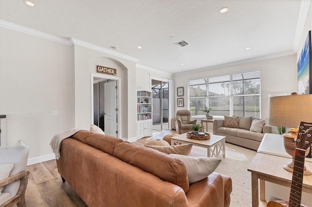 living room with a textured ceiling, crown molding, and light hardwood / wood-style flooring