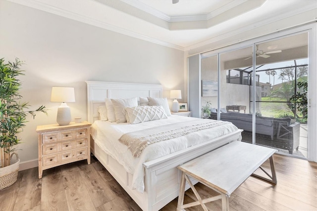 bedroom featuring access to outside, a raised ceiling, wood-type flooring, and ornamental molding