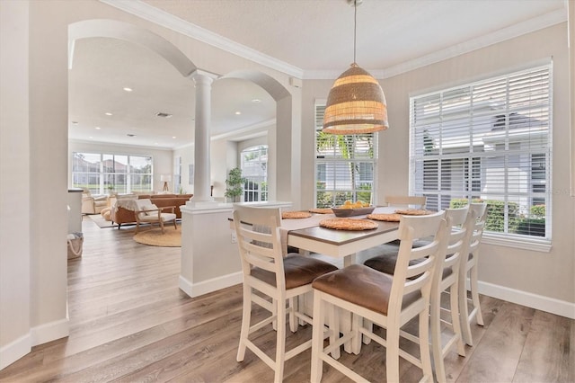 dining space featuring ornate columns, ornamental molding, and hardwood / wood-style flooring