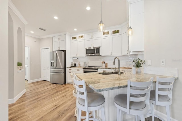 kitchen with a kitchen bar, appliances with stainless steel finishes, light stone countertops, sink, and hanging light fixtures