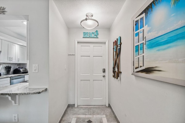 doorway to outside featuring light tile patterned floors and a textured ceiling