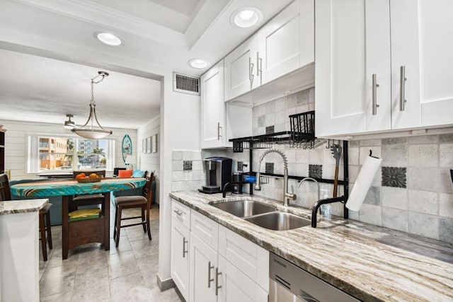 kitchen featuring white cabinets, light stone countertops, sink, and hanging light fixtures