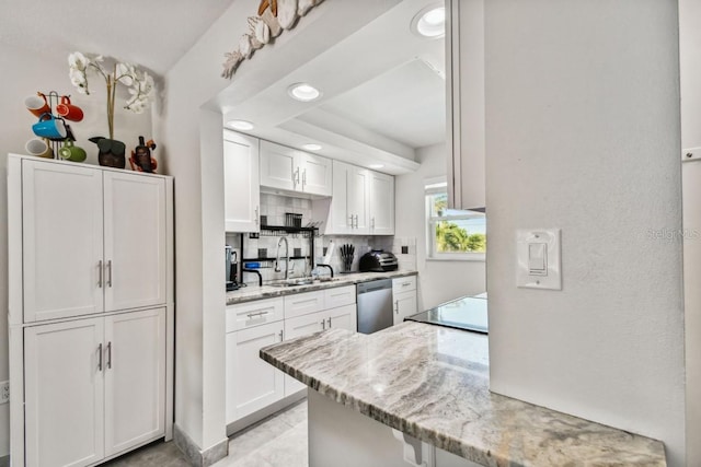 kitchen with white cabinetry, dishwasher, sink, light stone counters, and backsplash