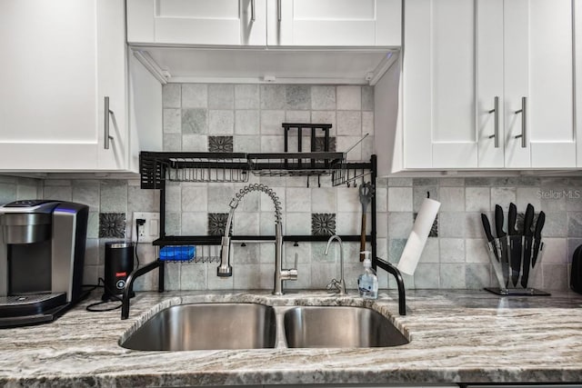 kitchen featuring white cabinets, light stone counters, sink, and tasteful backsplash