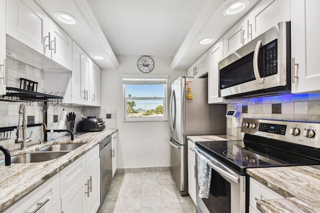 kitchen featuring light stone countertops, appliances with stainless steel finishes, tasteful backsplash, sink, and white cabinetry