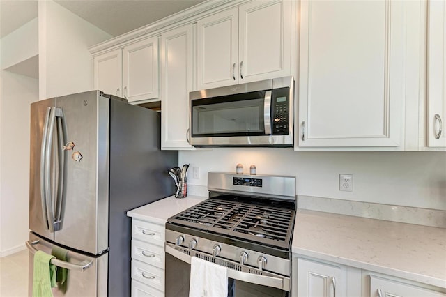 kitchen with light stone countertops, appliances with stainless steel finishes, and white cabinetry